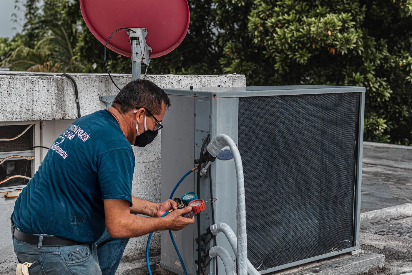 Technician checking refrigerant pressures on an outdoor condenser unit