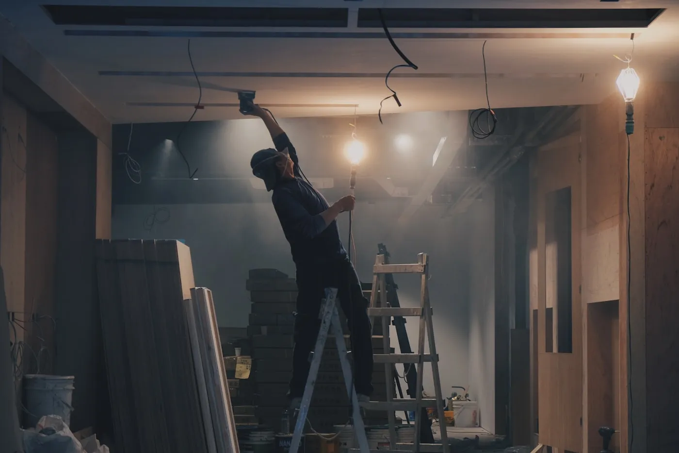 Technician on a step ladder replacing a ceiling light fitting