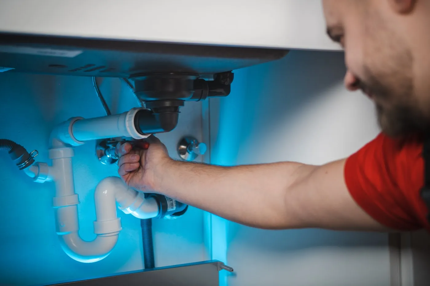 Plumber working on the pipework under a sink