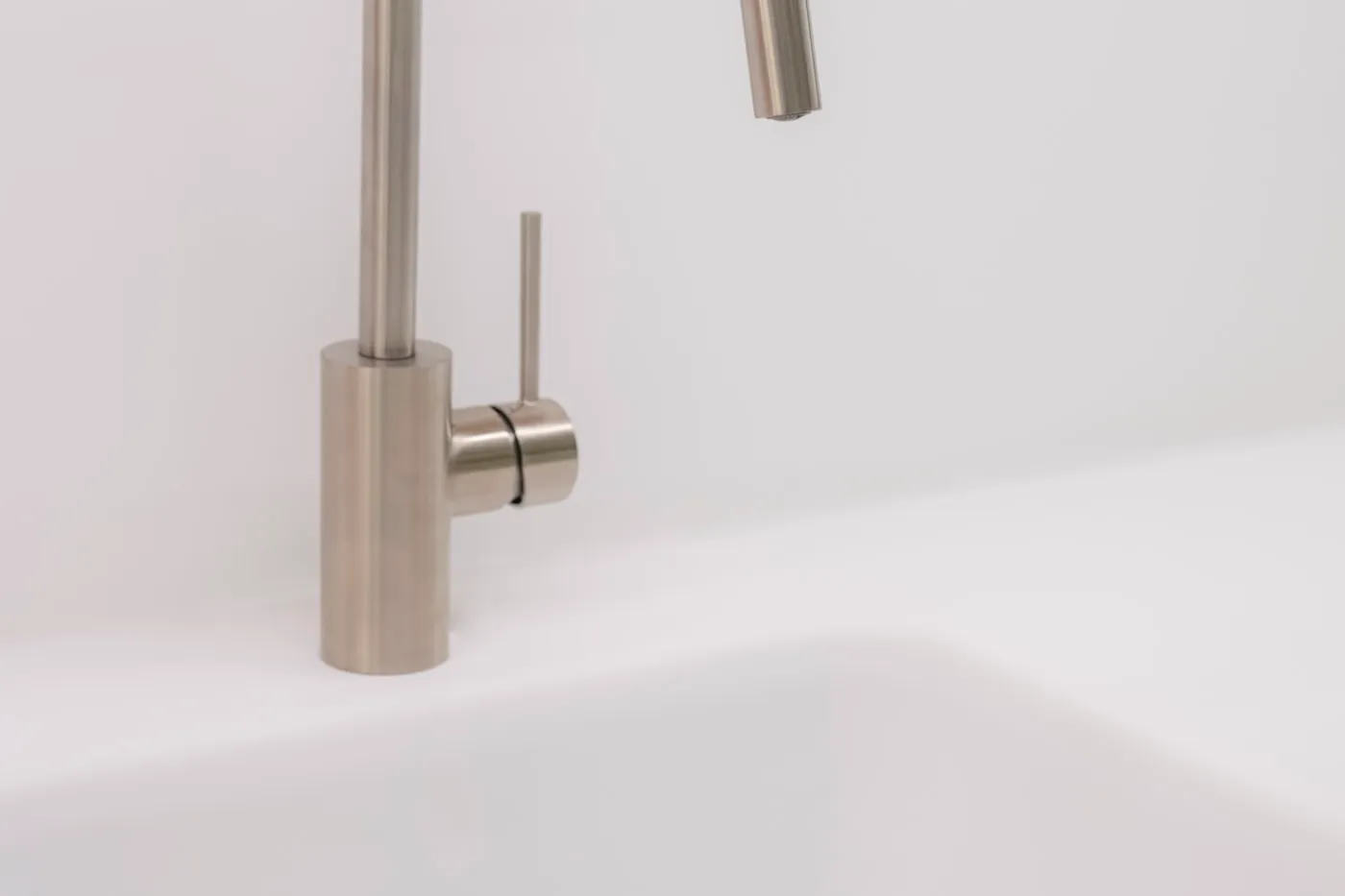 Stainless steel basin mixer tap over a white washroom basin